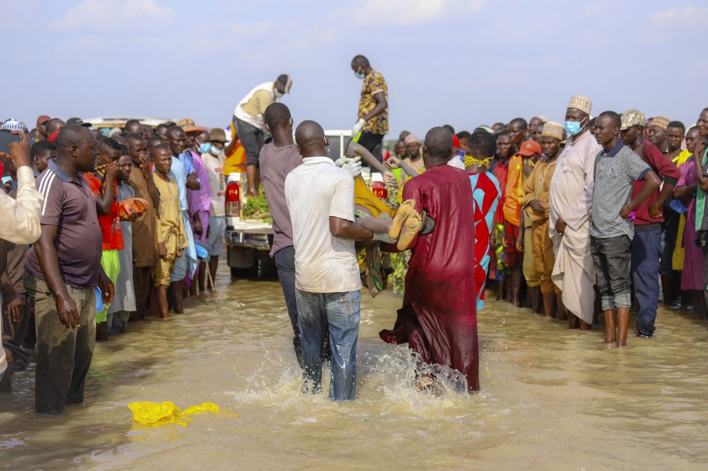 Hombres cargan un cuerpo rescatado del río. (Foto: - / AFP)