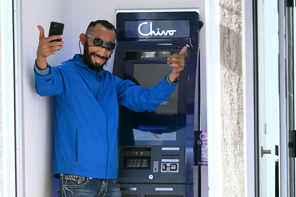 Un hombre con un cubrebocas con la imagen de Bukele posa en un cajero automático de bitcóin en San Salvador, el 7 de septiembre. (Foto: Marvin Recinos/AFP)