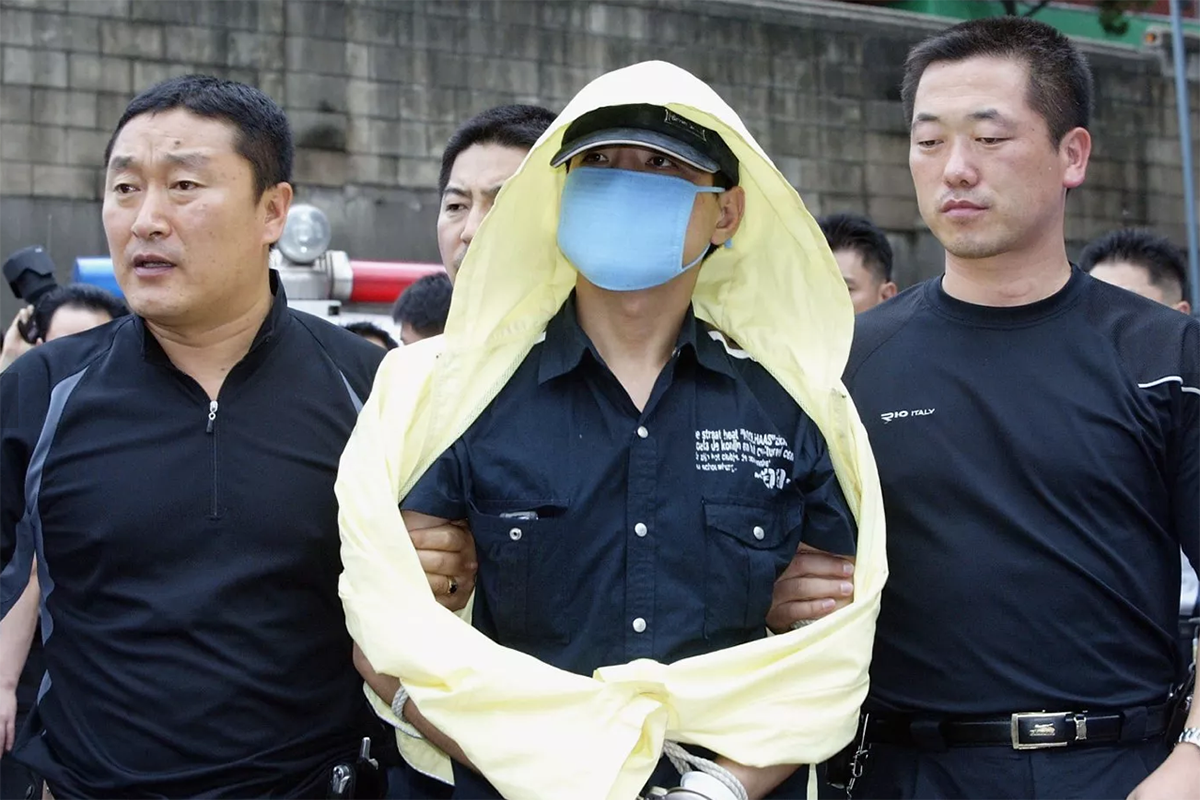 Yoo Young-Chul (centro) con la policía durante una inspección de los sitios donde presuntamente cometió sus asesinatos, el 19 de julio de 2004, en Seúl. (Foto: Kim Mi-Ok/Getty Images)