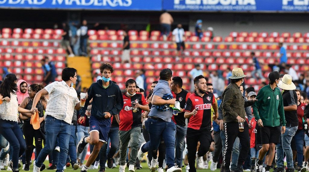 Ante la incapacidad de resolver los hechos, los escasos elementos de seguridad del estadio abrieron los accesos a la cancha para que la gente pudiera ponerse a salvo. (Foto: AFP)