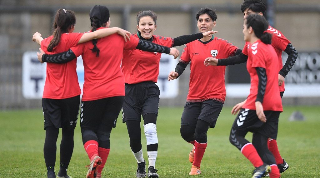 Afghan development squad team players celebrate after scoring during the football match between Afghan development squad and Womens parliamentary team, at the Dulwich Hamlet FC ground, in London, on March 29, 2022, as part of the Amnestys annual Football Welcomes month. - Under laughter and applause, Sabreyah and her teammates dribble and score during a football match against the women parliamentary team in a stadium in south London football. According to their coach, they exercise their "basic human rights", six months after fleeing Taliban-controlled Afghanistan. The young players left the country with their family and arrived in the UK in November 2021 on a flight funded by US Después de huir de Afganistán tras la toma del poder por los talibanes en agosto de 2021, las futbolistas y sus familias llegaron al Reino Unido en noviembre. (Foto: Justin Tallis/AFP)