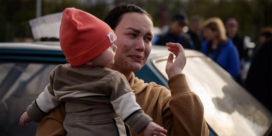 Una mujer llora mientras sostiene a un niño después de llegar de un territorio ocupado por Rusia a un área de registro y procesamiento para desplazados internos en Zaporiyia, Ucrania, el 2 de mayo de 2022. (Foto: Ed Jones/AFP)