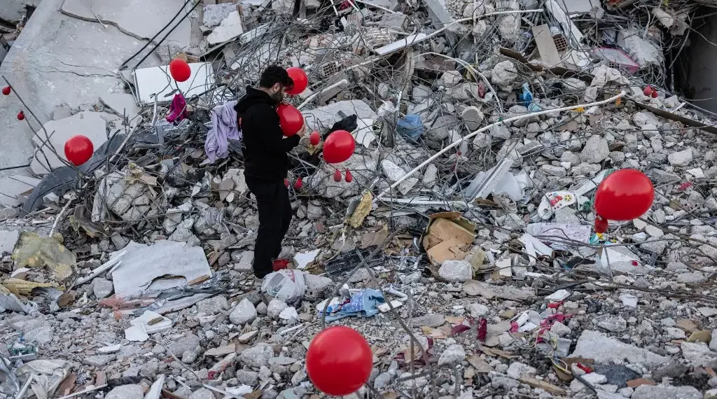 Ogun Sever Okur, hombre turco de 38 años, infla globos sobre los escombros de un edificio derrumbado en Antakya, al sur de Turquía. (AFP)