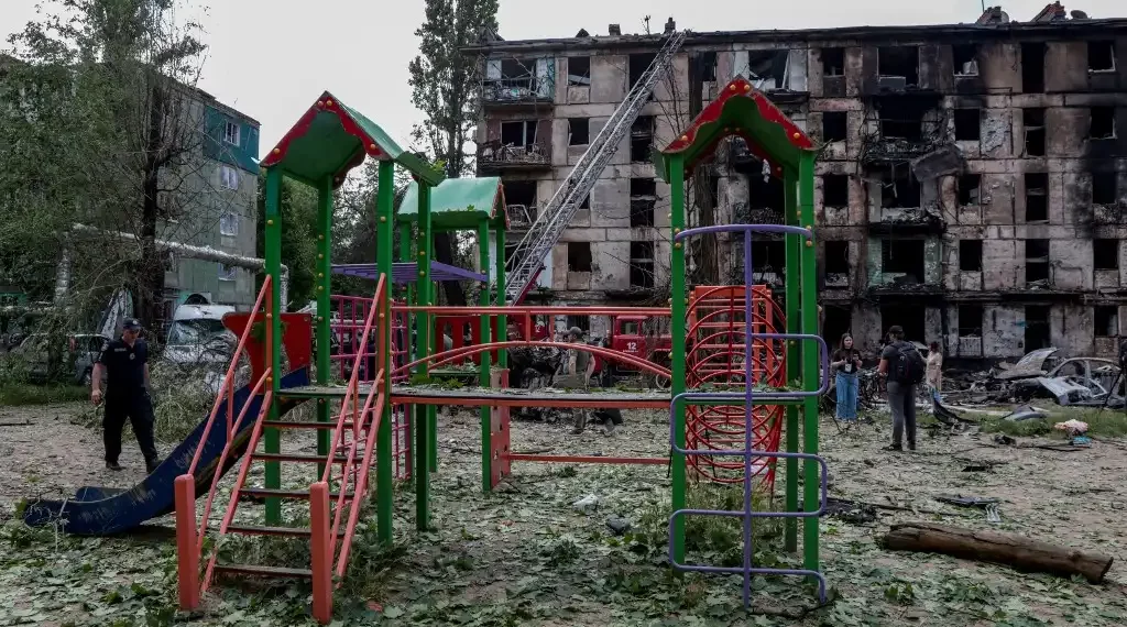 Un policía pasa frente a un parque infantil frente a un edificio residencial destruido tras un ataque ruso, en la ciudad de Krivói Rog. (AFP)