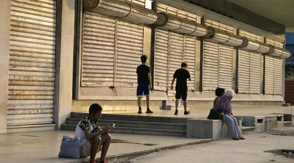 La gente pasa frente a un comercio cerrado antes de la llegada del huracán Rafael a La Habana. (AFP)