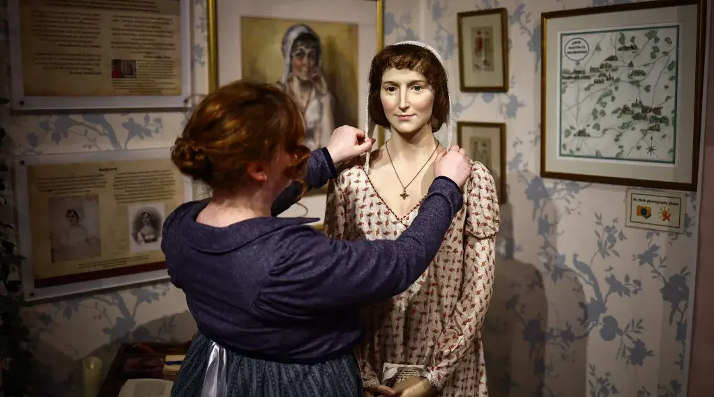 Una actriz de la época  que trabaja en el Centro Jane Austen ajusta un modelo de cera de Jane Austen en Bath, Somerset. (AFP)