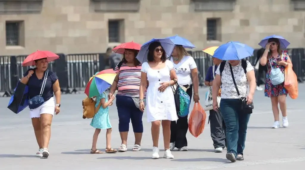 Una familia se protege de los rayos del sol utilizando sombrillas para sus cabezas. (Cuartoscuro)