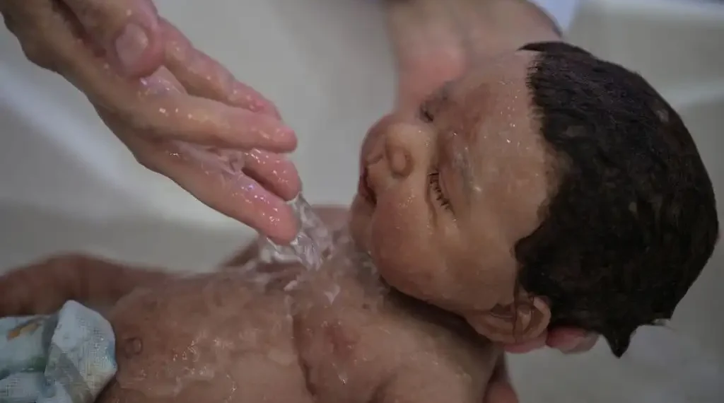 La comerciante brasileña Alana Generoso baña a una muñeca reborn en su tienda en Brasil. (AFP)