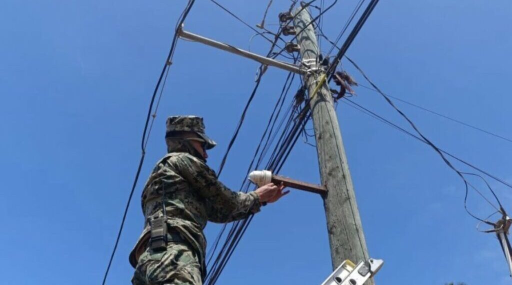 Elemento de la Secretaría de Marina desinstala cámara de videovigilancia ilegal instalada en poste público en Baja California.