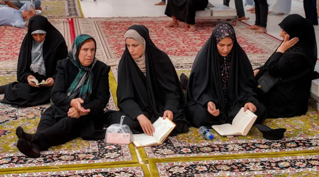 Fieles musulmanes leen el Corán, el libro sagrado del islam, mientras visitan con otros peregrinos iraníes el Santuario del Imán Alí en Nayaf, la ciudad sagrada central de Irak. (AFP)