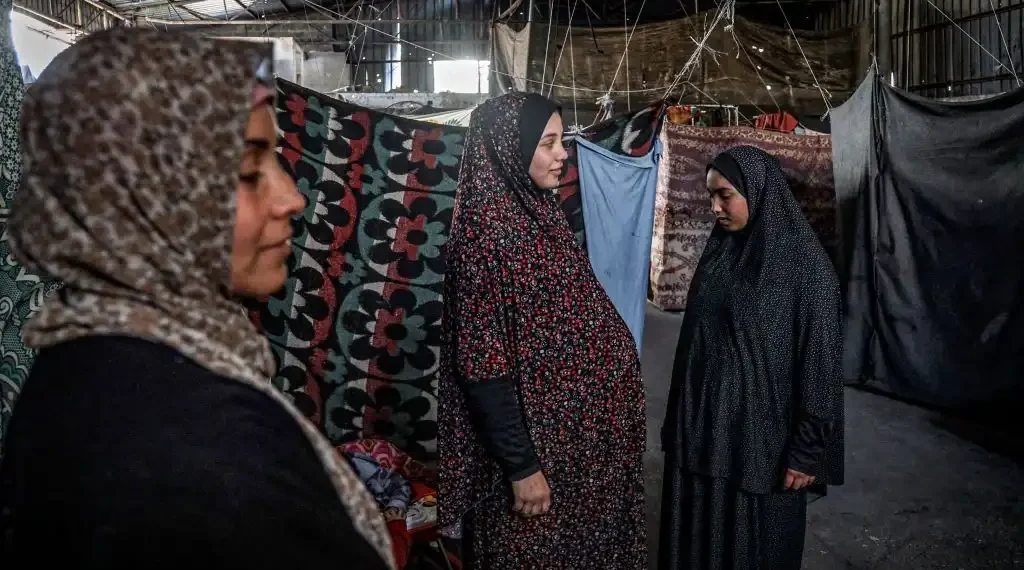 Una mujer palestina embarazada (centro) se encuentra en un almacén donde se refugia en Rafah, al sur de la Franja de Gaza. (AFP)