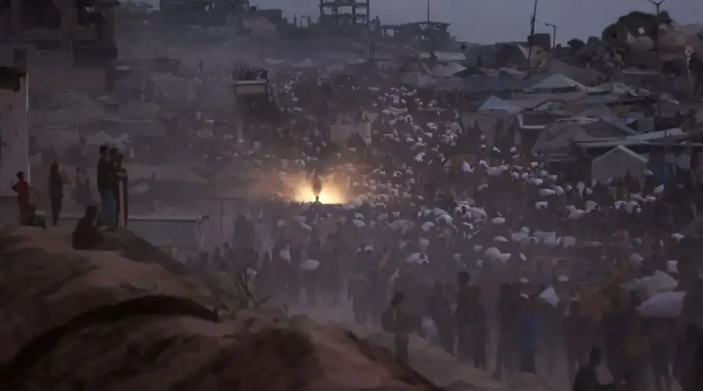 Palestinos regresan con paquetes de ayuda que consiguieron mientras caminan por un sendero costero al oeste de Beit Lahia el 29 de julio de 2025, después de que camiones de ayuda ingresaran a la Franja de Gaza asediada por Israel desde el cruce fronterizo norte de Zikim. (AFP)